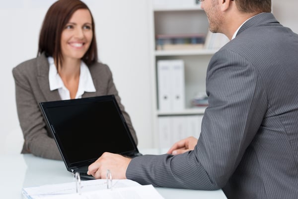 Businessman using a laptop computer in a meeting with a female colleague with focus to the blank screen of the computer