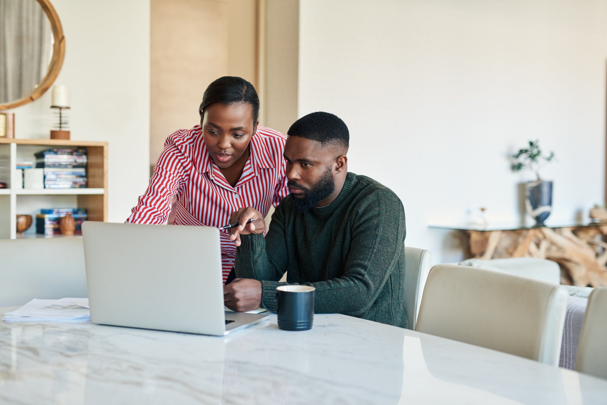 Young African American couple doing some online banking together at their dining room table at home